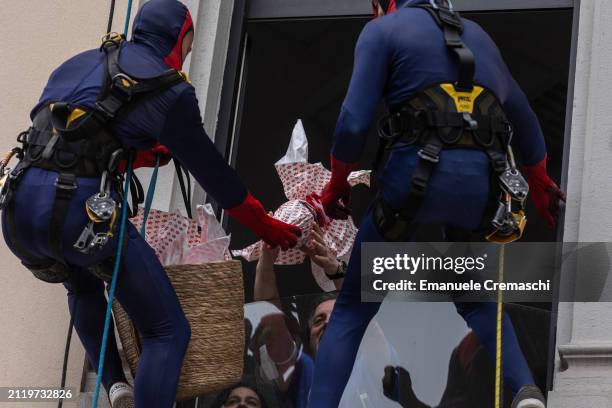 Rope access workers wearing comic-based superhero Spiderman costumes give chocolate Easter eggs to some relatives of hospitalized children at Clinica...