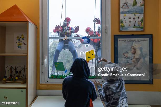 Rope access workers wearing comic-based superhero Spiderman costumes greet hospitalized children at Clinica Pediatrica De Marchi on March 28, 2024 in...