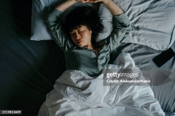 asian woman sleeping in her bed - slapen stockfoto's en -beelden