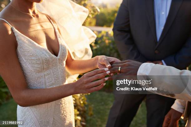 young bride exchanging wedding ring with groom - weding fotografías e imágenes de stock