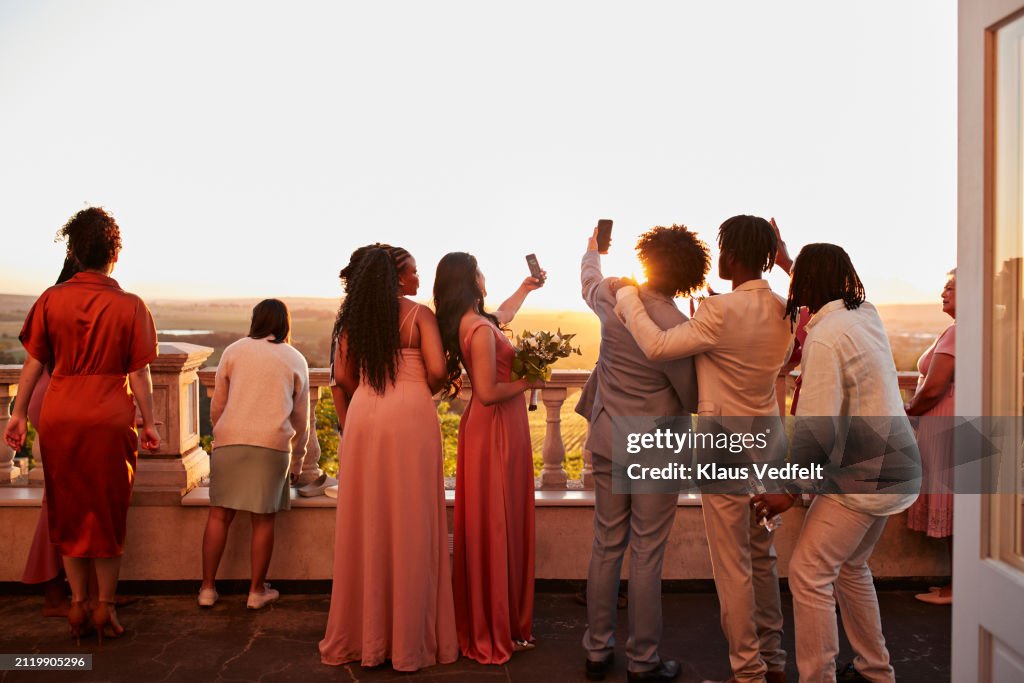 Guests taking selfie through smart phones at sunset