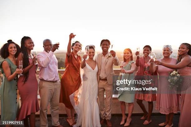 happy just married couple and guests toasting drinks - bruidsmeisje stockfoto's en -beelden