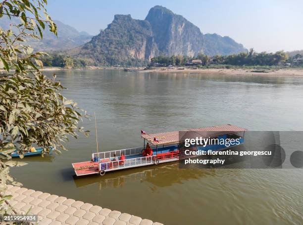 karst outcrops and riverboat viewed from pak ou tham ting (lower cave) buddha cave perched on a hilltop overlooking the mekong river, laos - tourboat stock pictures, royalty-free photos & images