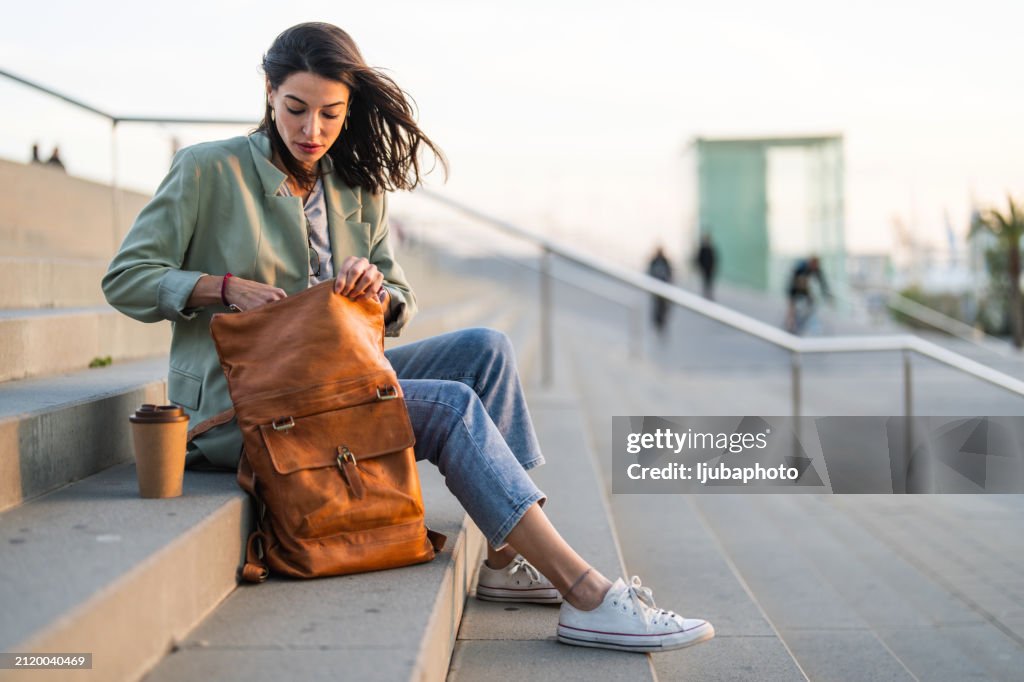 Smiling woman opening a backpack while sitting