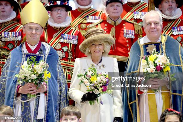 Queen Camilla holds a traditional Nosegay bouquet as she poses with Yeomen of the Guard and and religious representatives during The Royal Maundy...