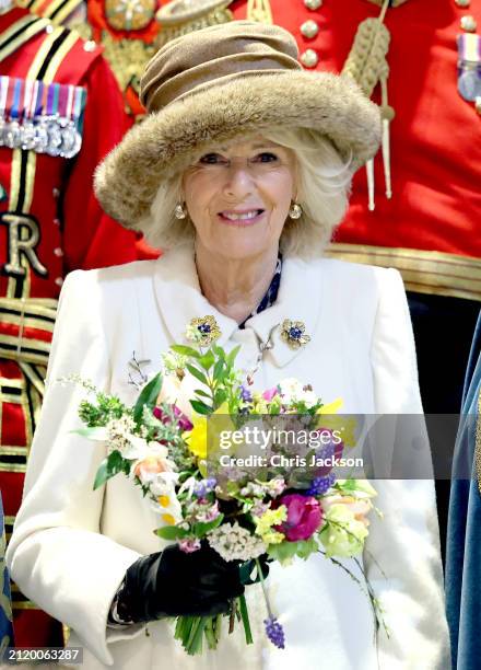 Queen Camilla holds a traditional Nosegay bouquet as she poses with Yeomen of the Guard and and religious representatives during The Royal Maundy...