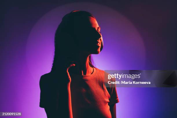 beautiful young woman enjoying music against multicolored background. - neon fluorescent hair stock-fotos und bilder