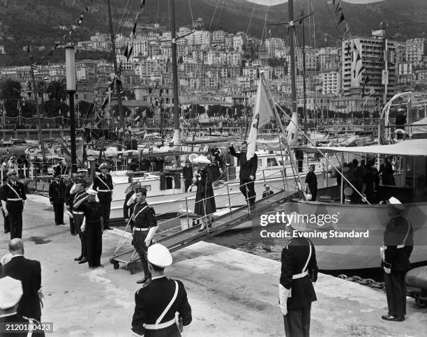 Grace Kelly and Prince Rainier arrive in Monaco from their yacht to a waiting honour guard, April 12th 1956. Kelly and Rainier were preparing for...