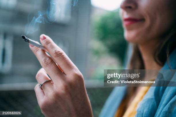 young woman smoking a cigarette outdoors. - smoking imagens e fotografias de stock