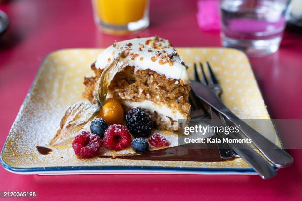 a slice of carrot cake on a plate with berries - carrot cake stock pictures, royalty-free photos & images