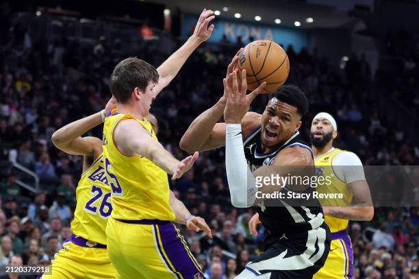 Giannis Antetokounmpo of the Milwaukee Bucks is fouled by Austin Reaves of the Los Angeles Lakers during a game at Fiserv Forum on March 26, 2024 in...