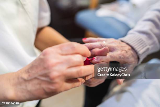 close-up of nurse applying red nail polish to elderly woman - nail polish stock pictures, royalty-free photos & images