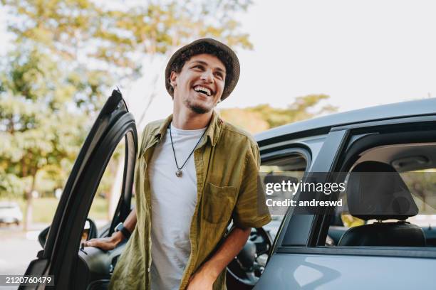 young man traveling by car getting out of the car - young men stock pictures, royalty-free photos & images