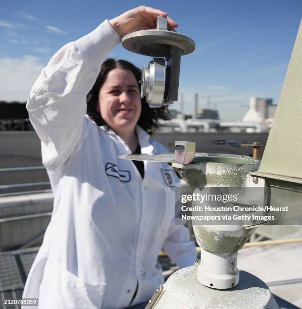 Microbiologist Christina Utz, demonstrates how she counts pollen daily by using a collection machine on the roof of the Houston Health Department on...