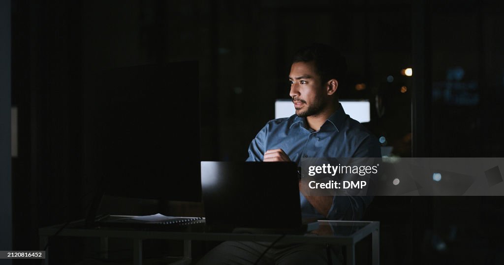 Young man, thinking and computer at night for information technology, programming or cybersecurity solution. Professional programmer or expert with problem solving or ideas on laptop in dark office
