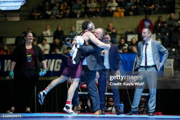 Bentley Schwanebeck-Ostermann of the Augsburg University Eagles hugs his coach after winning the 184 lb. Weights class and defeating Ryan DeVivo of...