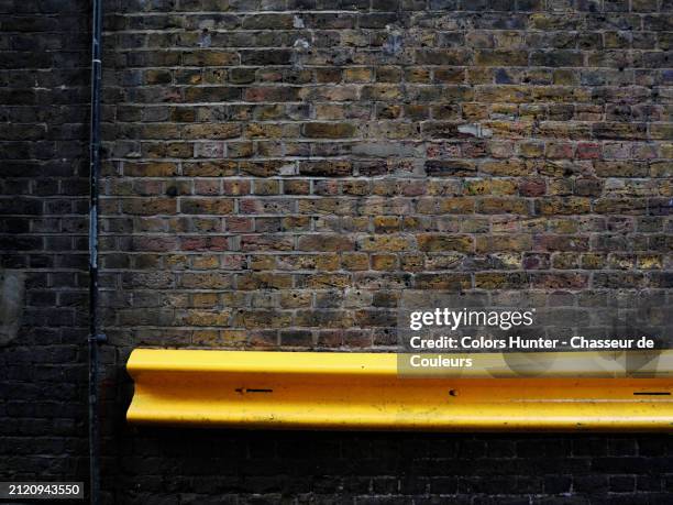 dark brown brick wall with metal tube and yellow guardrail. close-up of the gable of an old house in london, england, united kingdom. 
sunlight. natural colors. - steel railings stock pictures, royalty-free photos & images