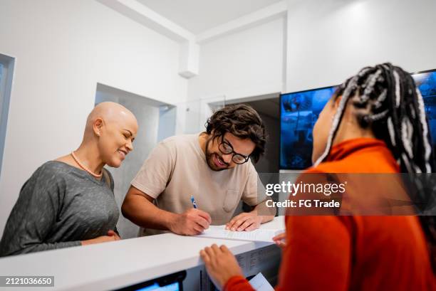 couple signing documents at medical clinic reception - registration form stock pictures, royalty-free photos & images