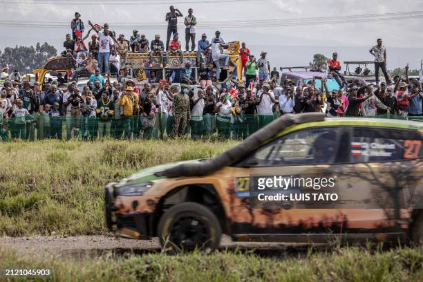 Spectators gather to watch from the sidelines as Polish driver Daniel Chwist steers his Skoda Fabia RS with Polish co-driver Kamil Heller during the...