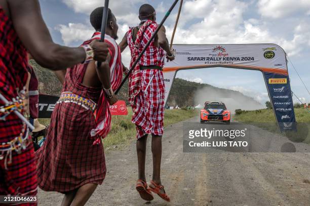 Maasai men jump at the finish line as Hyundai Shell Mobis World Rally Team's Estonian driver Ott Tanak steers his Hyundai i20 N Rally1 Hybrid with...