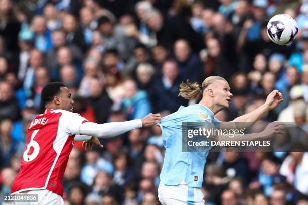 Arsenal's Brazilian defender Gabriel Magalhaes pulls the jersey of Manchester City's Norwegian striker Erling Haaland as they fight for the ball...