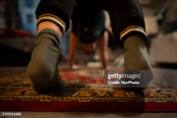 Woman is seen doing yoga exercises with YouTube trainer on a television in her living room in Warsaw, Poland on 23 March, 2024.