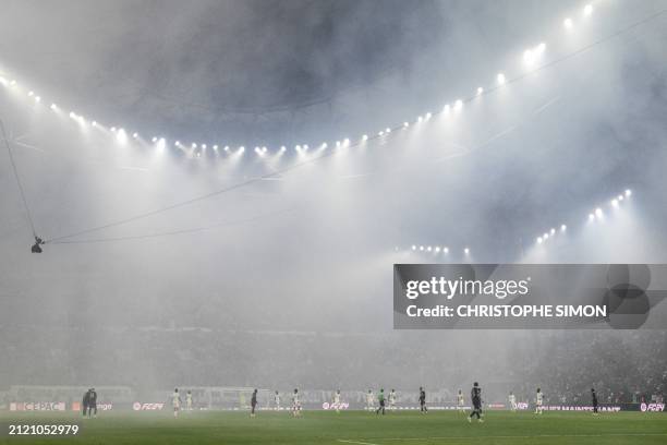 General view shows smoke and rain in the stadium at the start of the French L1 football match between Olympique Marseille and Paris Saint-Germain at...