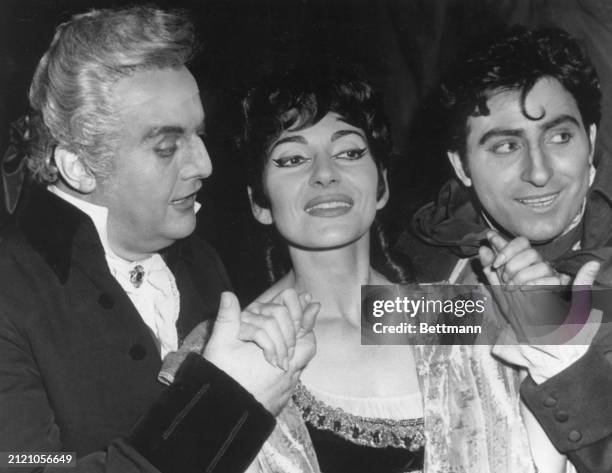Soprano Maria Callas holds hands with fellow opera stars Tito Bobbi and Renato Cioni, following her performance in the title role of "Tosca" at the...