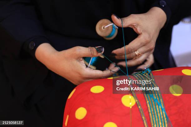 An Emirati woman weaves thread in the Al Talli method, a traditional local weaving technique, during an annual heritage festival in Al-Ain on...