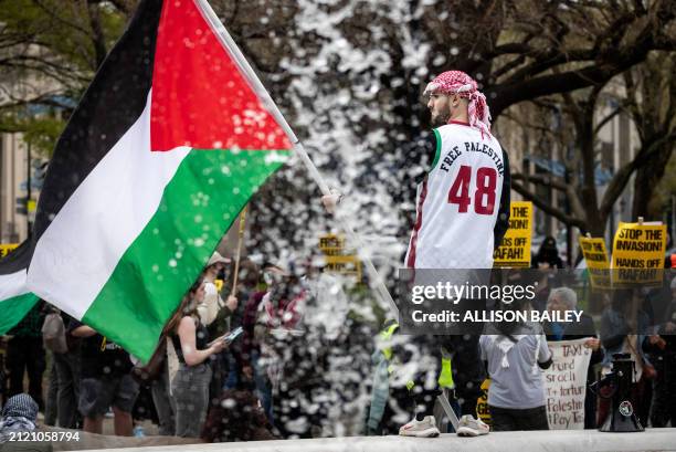 Rafat Abu-Ghannam stands on the DuPont Circle fountain during a demonstration observing Palestinian Land Day, one of hundreds of protests worldwide,...