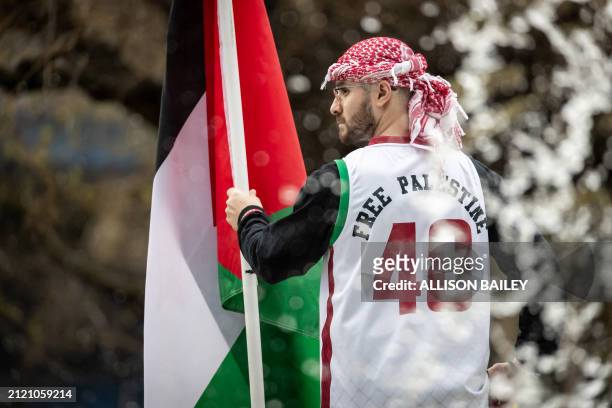 Rafat Abu-Ghannam stands on the DuPont Circle fountain during a demonstration observing Palestinian Land Day, one of hundreds of protests worldwide,...