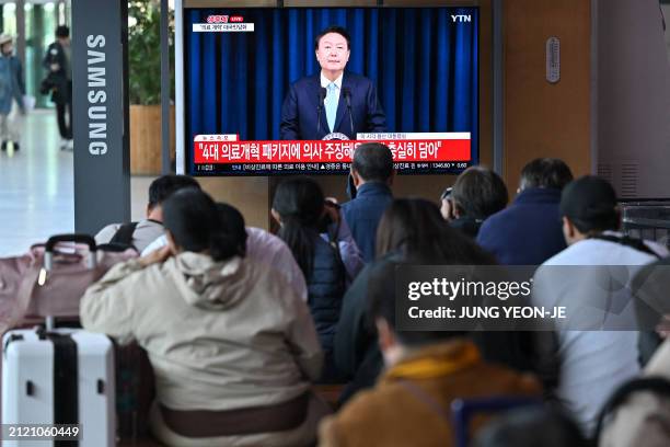 People watch a television news programme broadcasting live footage of South Korean President Yoon Suk Yeol delivering a speech on his medical reform...