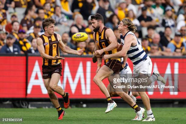 Conor Nash of the Hawks handpasses the ball to Dylan Moore of the Hawks as he's tackled by Mark Blicavs of the Cats during the 2024 AFL Round 03...