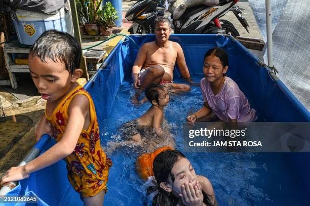 Children and an adult cool off in a makeshift pool beside a street on a hot day in Manila on April 1, 2024.