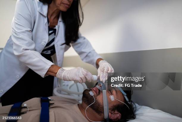ärztin legt patientin im krankenhaus sauerstoffmaske auf - schlafapnoe stock-fotos und bilder