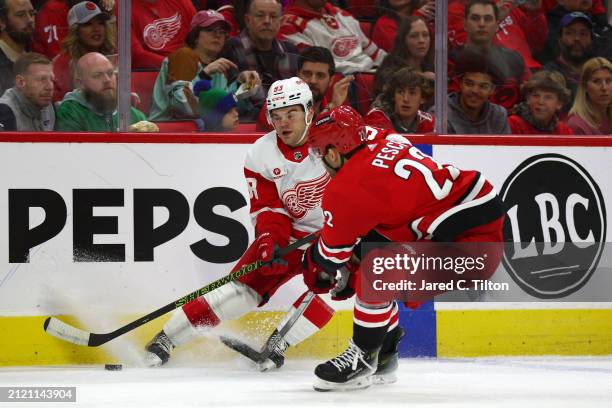 Alex DeBrincat of the Detroit Red Wings and Stefan Noesen of the Carolina Hurricanes work for possession of the puck during the first period of the...