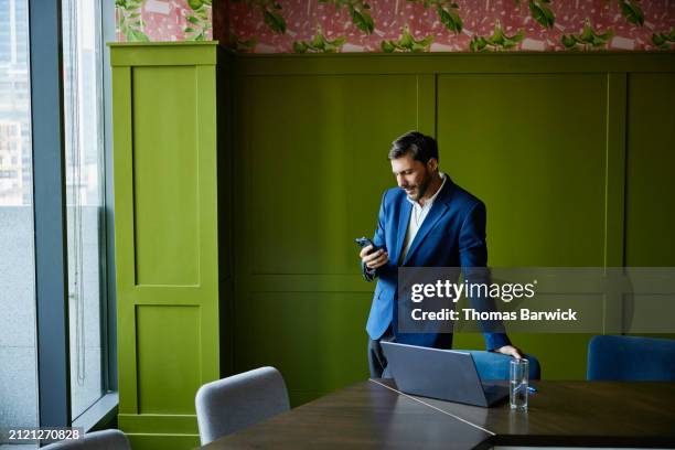 medium wide shot businessman using smartphone for video call in office - green suit stock pictures, royalty-free photos & images