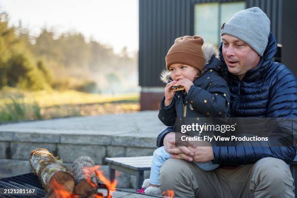 toddler girl eating s'mores while on winter family vacation - chinese eating backyard stock pictures, royalty-free photos & images