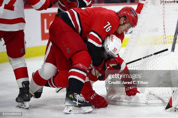 Brady Skjei of the Carolina Hurricanes takes David Perron of the Detroit Red Wings to the ground during the third period of the game at PNC Arena on...