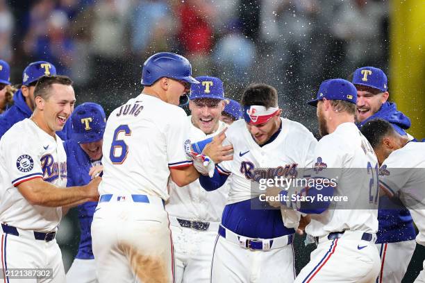 Jonah Heim of the Texas Rangers is congratulated by teammates following a walk-off single in the 11th inning to defeat the Chicago Cubs in the...