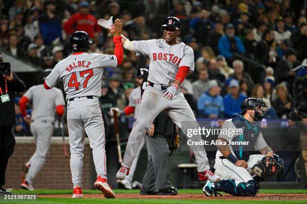 Rafael Devers of the Boston Red Sox celebrates with Enmanuel Valdez after hitting a two-run home run during the third inning of the Opening Day game...