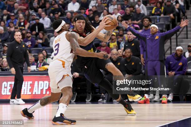 Aaron Gordon of the Denver Nuggets drives against Bradley Beal of the Phoenix Suns during the third quarter at Ball Arena on March 27, 2024 in...