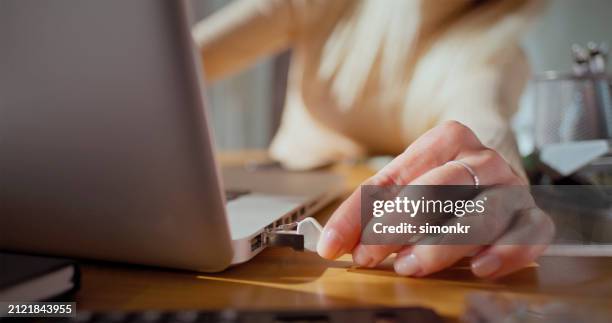 woman connecting network cord plug into laptop - tomada de ligação à rede imagens e fotografias de stock