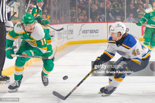 Adam Beckman of the Minnesota Wild and Scott Perunovich of the St. Louis Blues battle for the puck during the game at the Xcel Energy Center on March...