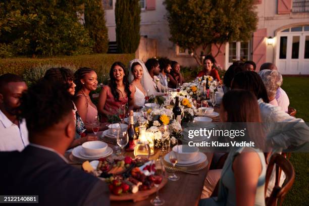 guests with newlywed groom and bride at table - 70s wedding black couple stock pictures, royalty-free photos & images