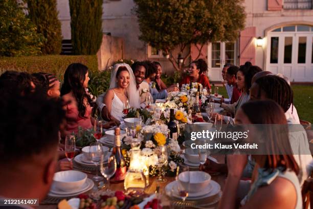 guests with newlywed bride and groom at table - invité photos et images de collection