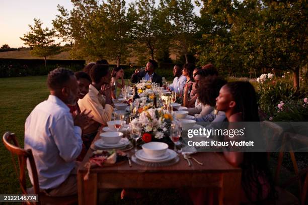 wedding guests sitting together at long dining table - middagsbjudning bildbanksfoton och bilder