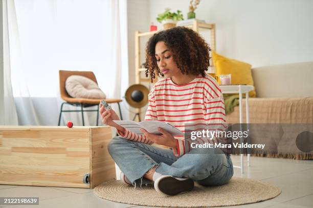 mujer leyendo instrucciones para armar un armario en casa - manual fotografías e imágenes de stock