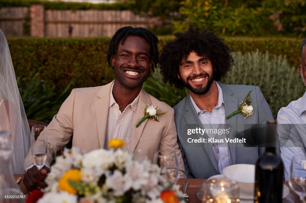 Cheerful groom and best man sitting at dining table