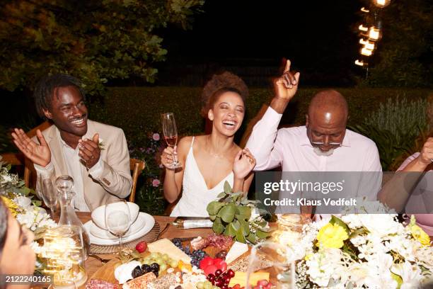 cheerful guests and newlywed couple enjoying dinner party - 70s wedding black couple stock pictures, royalty-free photos & images